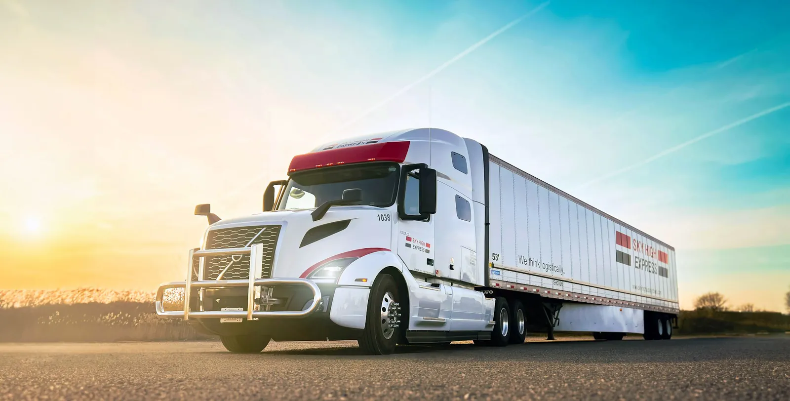 Fleet of semi-trucks on a highway at sunset